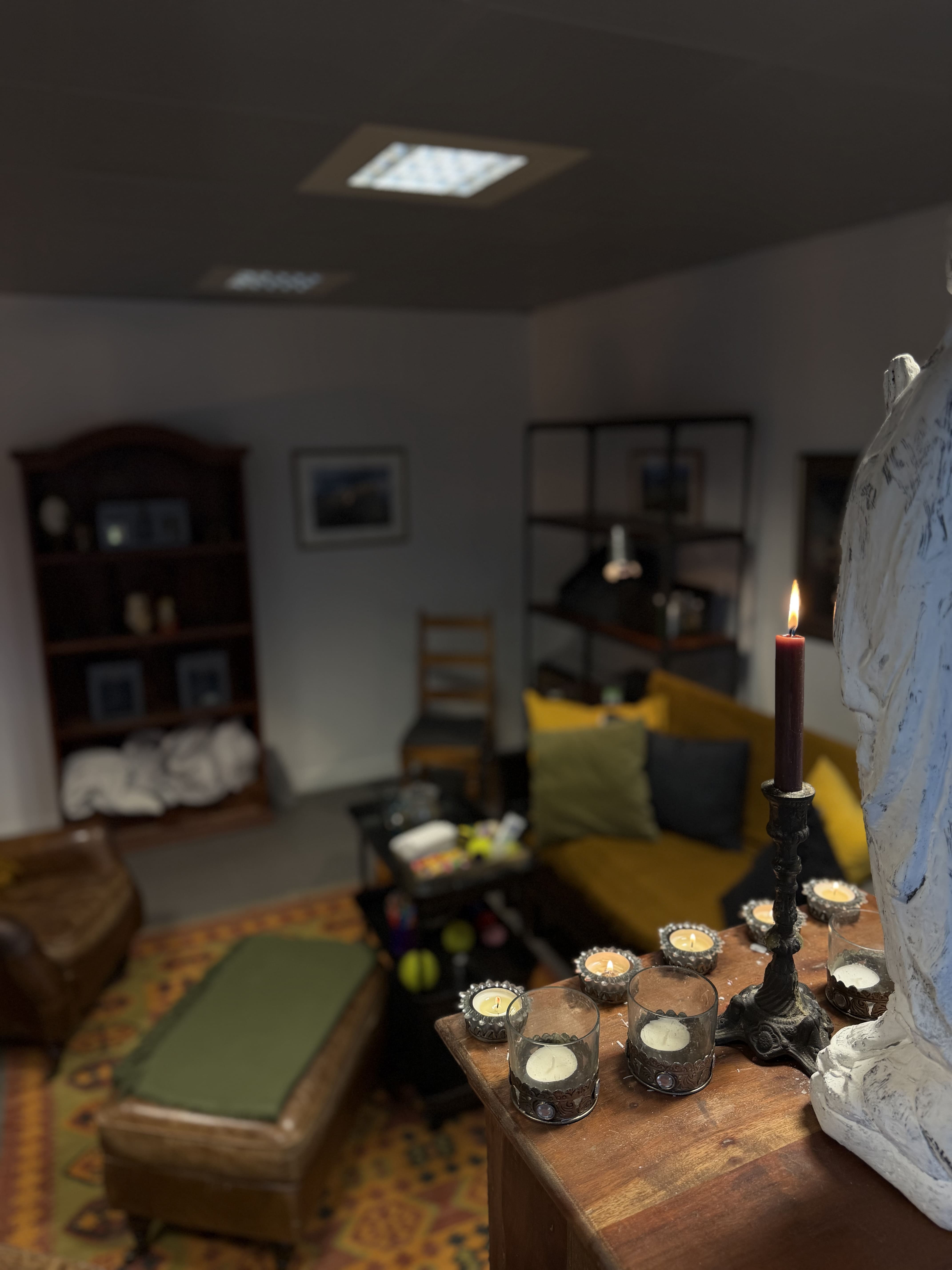 Sohvahuone, jossa oranssinruskea sohva, kynttiläjalka ja useita pieniä tuikkuja pöydällä.